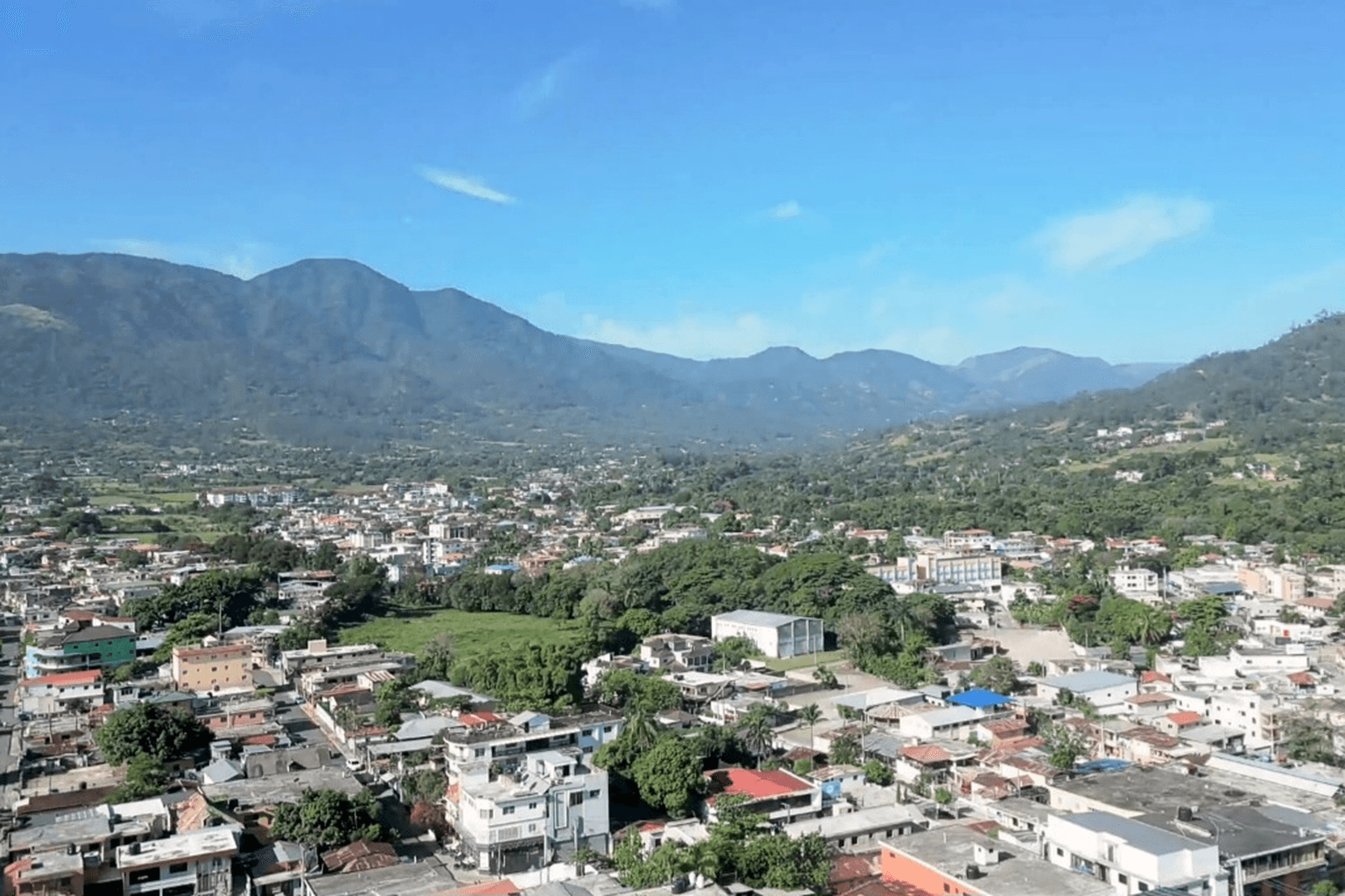 Downtown Jarabacoa spread across a green mountain valley beneath a broad mountain ridge.
